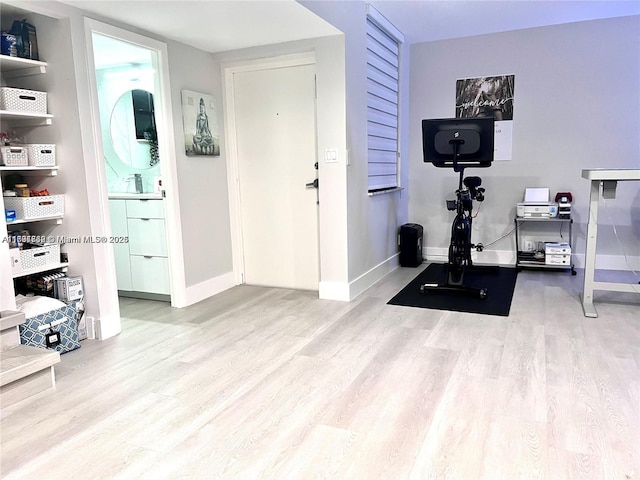 exercise room featuring a sink, wood finished floors, and baseboards