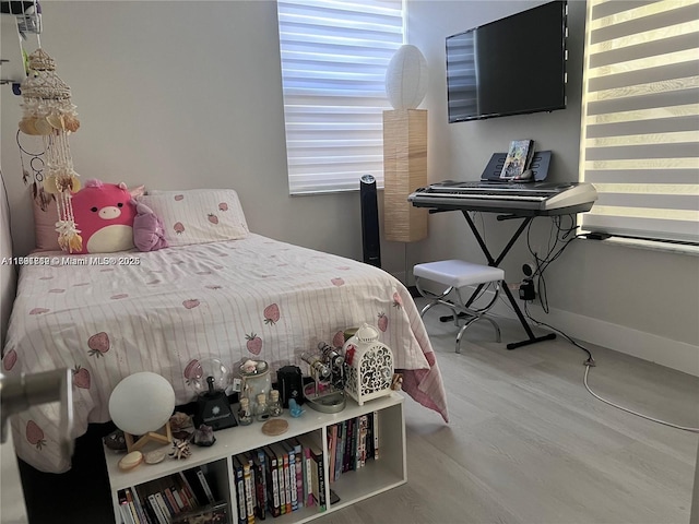 bedroom featuring wood finished floors, baseboards, and multiple windows