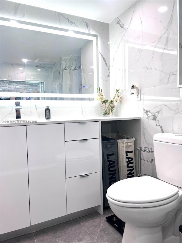 bathroom with tile walls, marble finish floor, toilet, and vanity