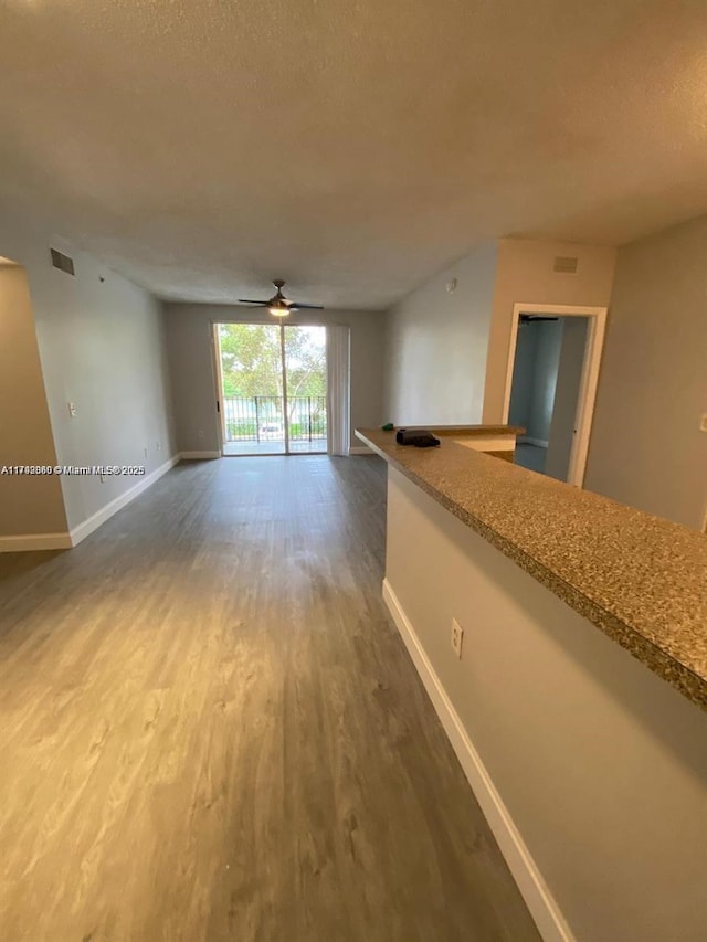 2351 W Preserve Way Unit 205, Miramar, FL 33025 - unfurnished living room featuring a textured ceiling, ceiling fan, visible vents, baseboards, and wood finished floors