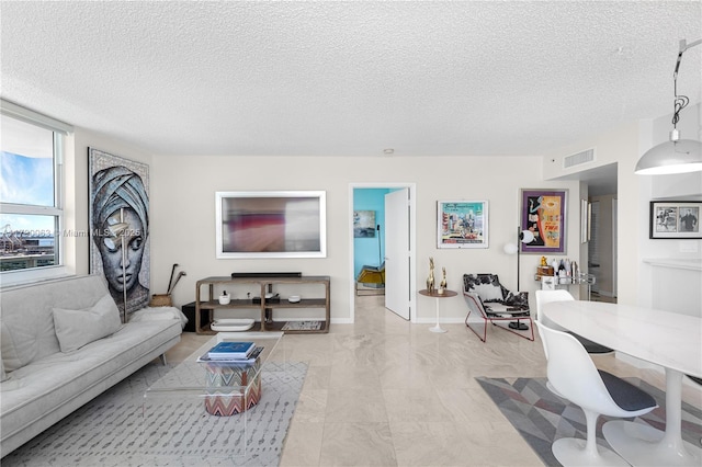 living room featuring visible vents, a textured ceiling, and baseboards