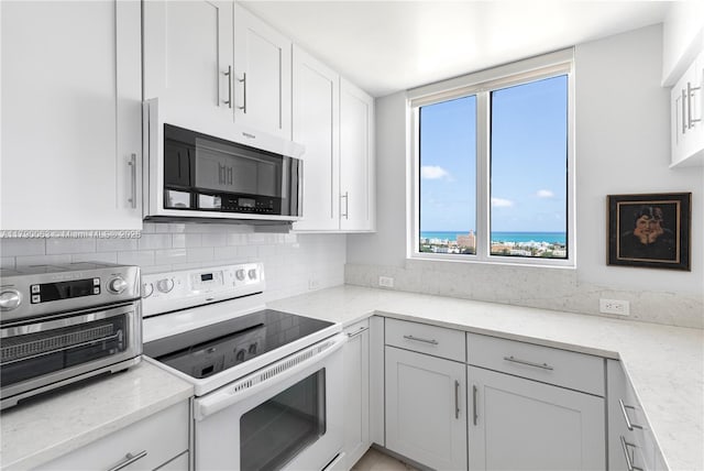 kitchen with a healthy amount of sunlight, decorative backsplash, white range with electric cooktop, and stainless steel microwave
