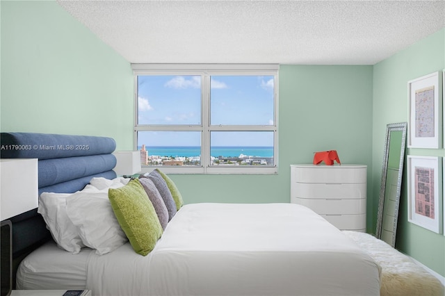 bedroom featuring a water view and a textured ceiling