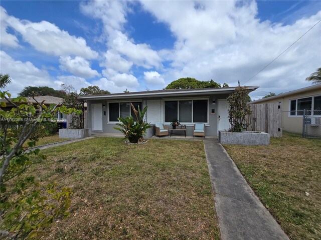2281 NE 173rd St, North Miami Beach, FL 33160 - view of front of house featuring a front lawn, an outdoor living space, central AC unit, and fence
