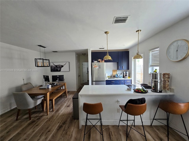2281 NE 173rd St, North Miami Beach, FL 33160 - kitchen featuring dark wood-style floors, a kitchen bar, blue cabinetry, visible vents, and a peninsula