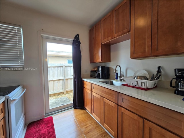 2281 NE 173rd St, North Miami Beach, FL 33160 - kitchen with white range with electric cooktop, a sink, brown cabinets, and light countertops