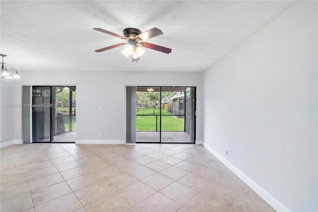5000 S University Dr, Davie, FL 33328 - empty room featuring ceiling fan with notable chandelier, light tile patterned floors, a healthy amount of sunlight, and a textured ceiling