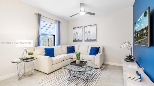 living area with light tile patterned floors, a ceiling fan, and baseboards