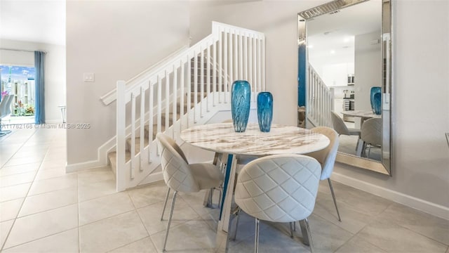 dining room featuring light tile patterned floors, stairs, and baseboards