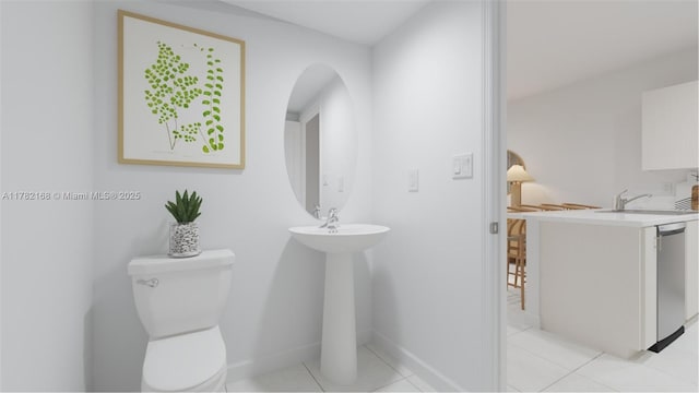 bathroom with baseboards, toilet, tile patterned flooring, and a sink