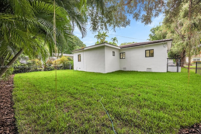 305 Fluvia Ave, Coral Gables, FL 33134 - rear view of house featuring stucco siding, fence, and a yard