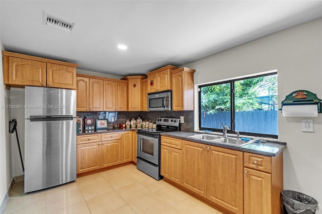 kitchen with decorative backsplash, appliances with stainless steel finishes, a sink, visible vents, and light tile patterned flooring