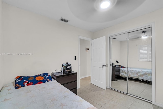 bedroom featuring light tile patterned flooring, visible vents, baseboards, and a closet