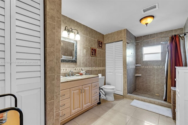 bathroom featuring a tile shower, tile patterned floors, a closet, tile walls, and visible vents