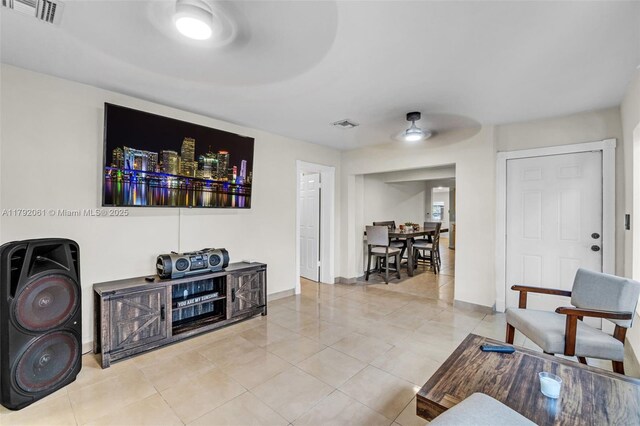 living room with light tile patterned flooring, a ceiling fan, visible vents, and baseboards