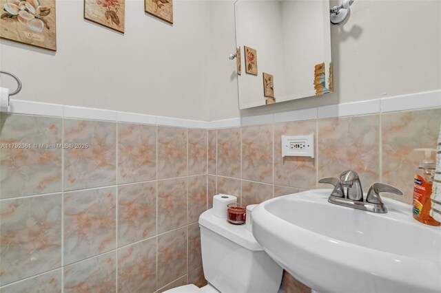 bathroom with tile walls, toilet, and a sink