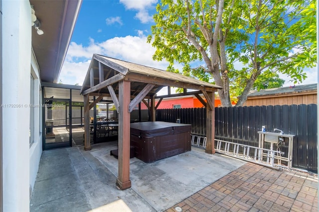 view of patio / terrace featuring fence, a gazebo, and a hot tub