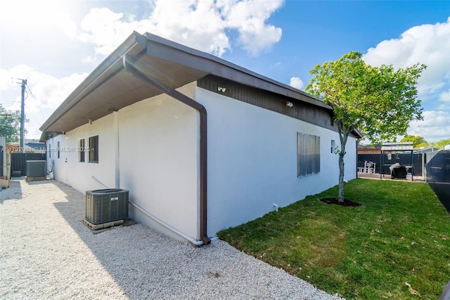 view of property exterior featuring fence, stucco siding, cooling unit, and a lawn