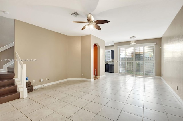 empty room with arched walkways, stairs, light tile patterned floors, visible vents, and a ceiling fan