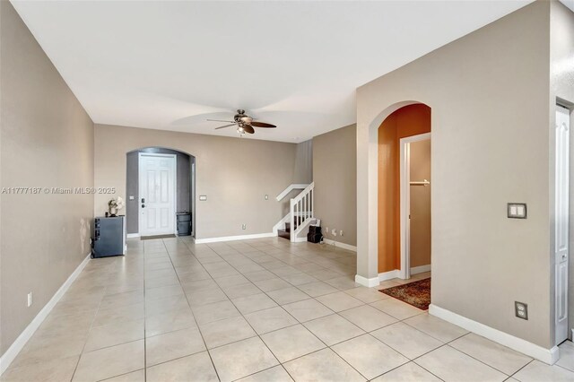 4343 Chalmers Ln, West Palm Beach, FL 33417 - spare room featuring arched walkways, a ceiling fan, stairway, and light tile patterned floors