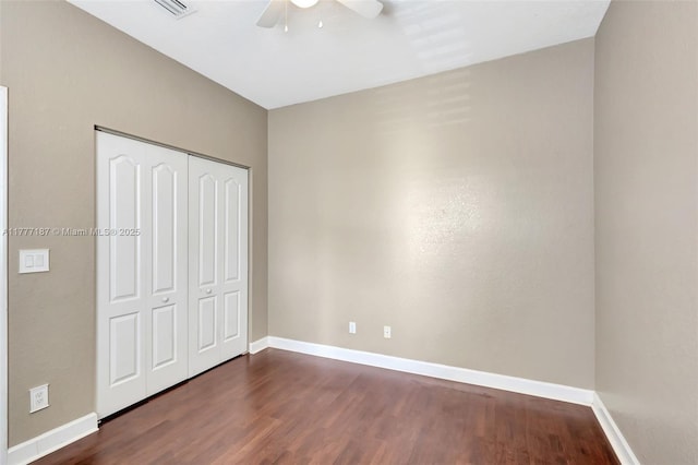 unfurnished bedroom with dark wood-type flooring, a closet, and baseboards