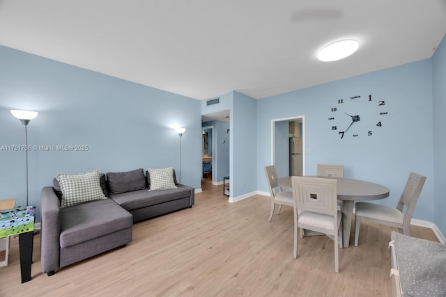 living area featuring visible vents, baseboards, and light wood-style floors