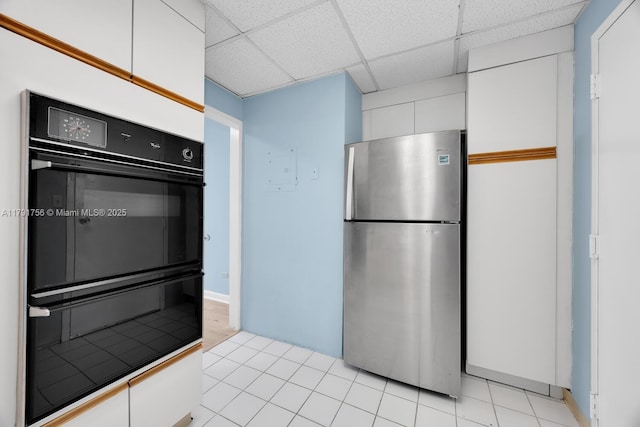 kitchen featuring a paneled ceiling, white cabinets, freestanding refrigerator, and dobule oven black