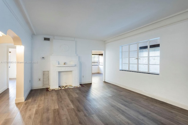 unfurnished living room with wood finished floors, visible vents, and arched walkways