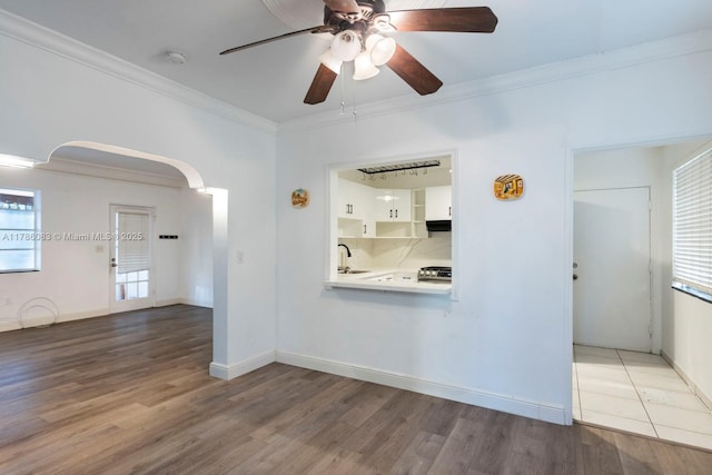 unfurnished living room featuring crown molding, a sink, ceiling fan, and a healthy amount of sunlight