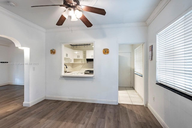 unfurnished room featuring ceiling fan, light wood-type flooring, ornamental molding, and a sink