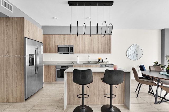 3900 Biscayne Blvd Unit S-920, Miami, FL 33137 - kitchen featuring appliances with stainless steel finishes, modern cabinets, a kitchen bar, light countertops, and light brown cabinetry