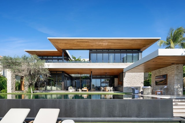 back of property featuring a water view and stone siding