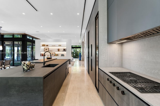 kitchen featuring a large island, modern cabinets, recessed lighting, light wood-type flooring, and a sink