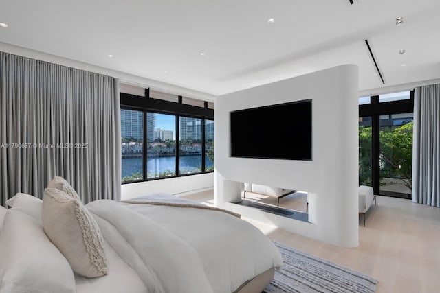 bedroom with recessed lighting, wood finished floors, and expansive windows