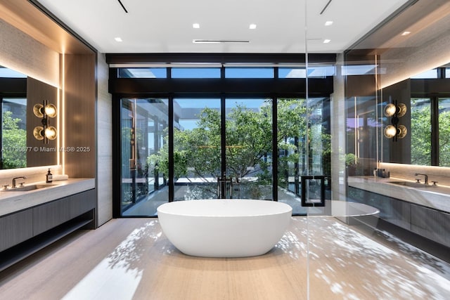 bathroom featuring vanity, wood finished floors, and a soaking tub