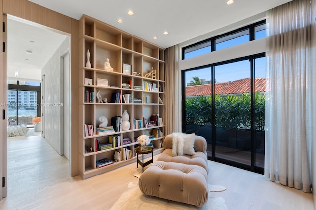 living area with wood finished floors, a healthy amount of sunlight, and built in shelves