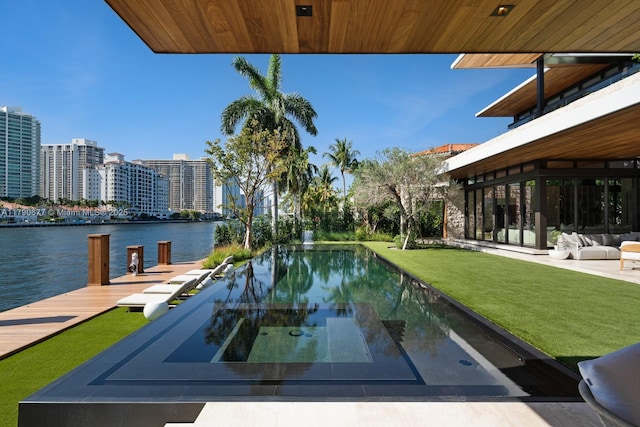 view of pool featuring a yard, a water view, a view of city, and a boat dock