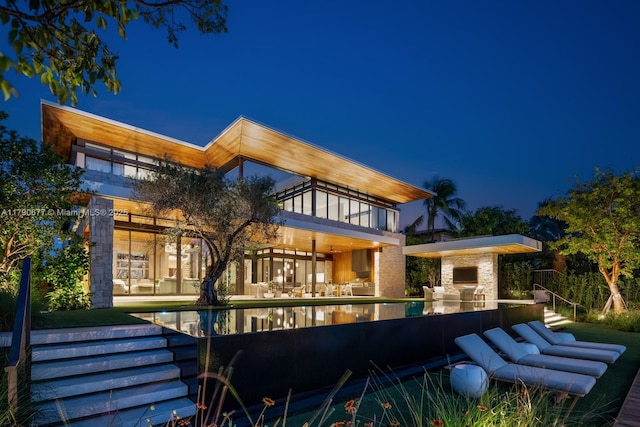 194 S Island Dr, Golden Beach, FL 33160 - back of house at twilight featuring a balcony, a patio area, and an outdoor pool