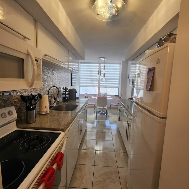 kitchen featuring a sink, white appliances, white cabinetry, light tile patterned floors, and tasteful backsplash
