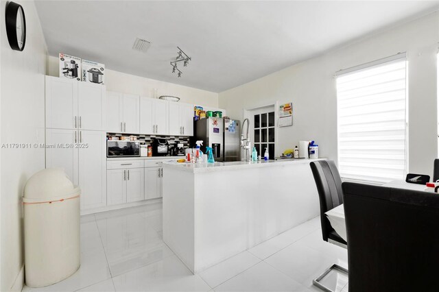 1922 NW 4th St, Miami, FL 33125 - kitchen featuring visible vents, white cabinetry, a peninsula, stainless steel refrigerator with ice dispenser, and backsplash