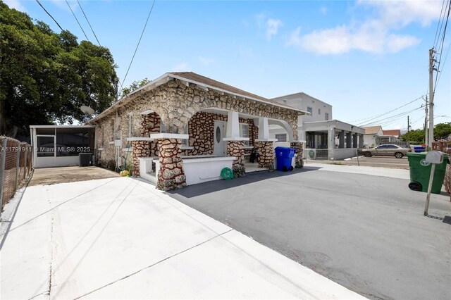 1922 NW 4th St, Miami, FL 33125 - view of front of house featuring central AC unit, fence, and stone siding