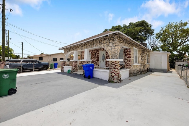 1922 NW 4th St, Miami, FL 33125 - view of front of home featuring a chimney, stone siding, and fence