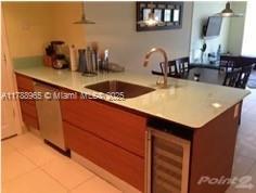 5875 Collins Ave Unit 1006, Miami Beach, FL 33140 - kitchen featuring wine cooler, brown cabinets, light countertops, and a sink