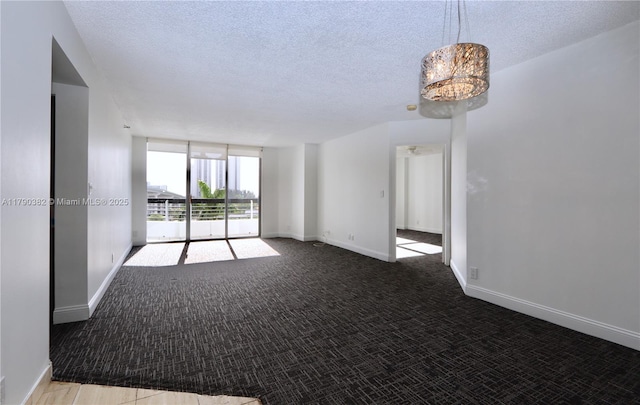 empty room with a textured ceiling, carpet, and baseboards