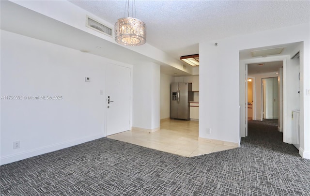 carpeted foyer featuring baseboards, visible vents, a textured ceiling, and tile patterned flooring