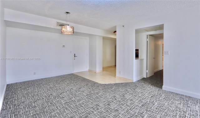 carpeted spare room featuring a textured ceiling, visible vents, and baseboards
