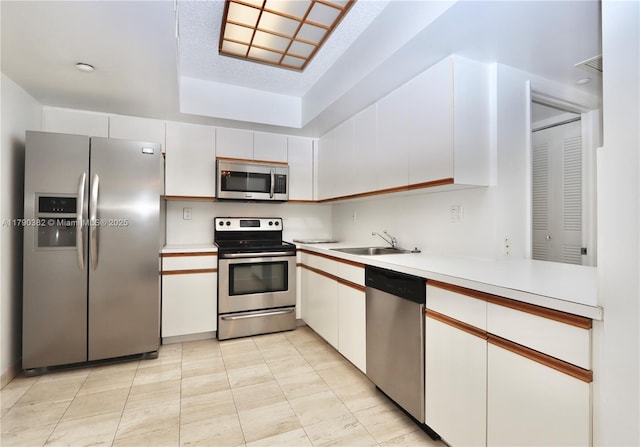 kitchen featuring white cabinetry, stainless steel appliances, light countertops, and a sink