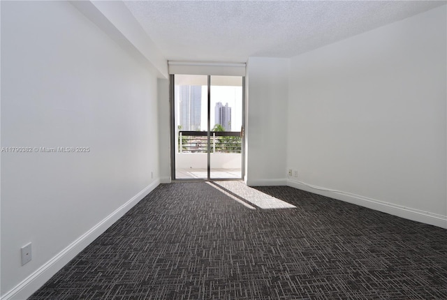 empty room with baseboards, dark carpet, a wall of windows, and a textured ceiling