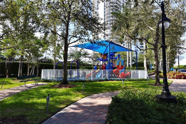 view of home's community with fence, playground community, and a yard