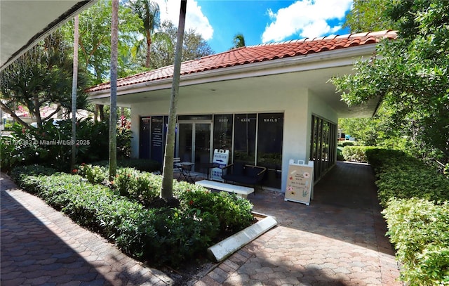 rear view of house with stucco siding and a tile roof